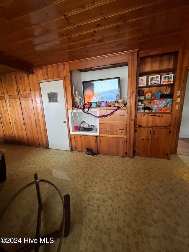 interior space featuring wooden walls, carpet, and wooden ceiling