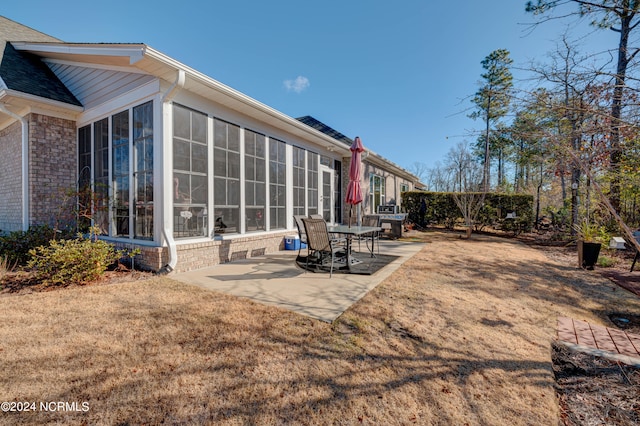 rear view of property featuring a yard, a patio, and a sunroom