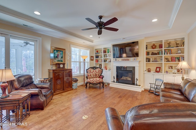 living room with built in shelves, light hardwood / wood-style flooring, and crown molding