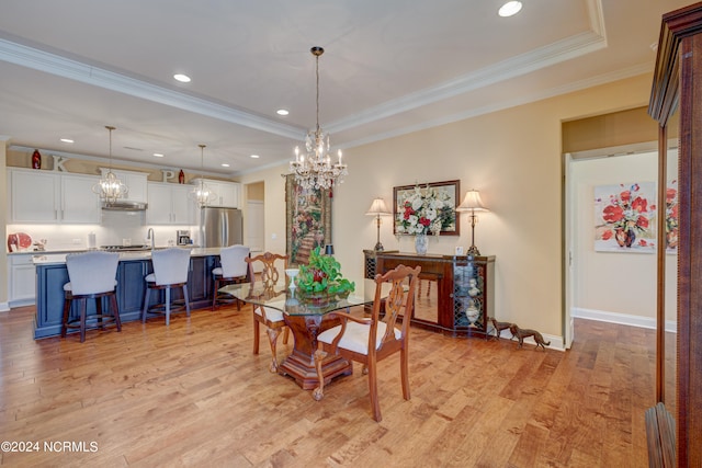 dining area with light hardwood / wood-style floors, a raised ceiling, and crown molding