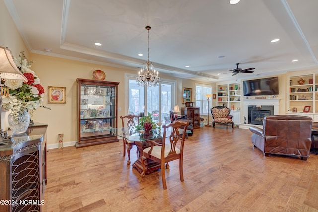 dining room featuring a raised ceiling, crown molding, light hardwood / wood-style flooring, and ceiling fan with notable chandelier