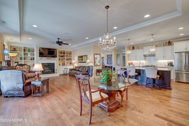 dining area with ceiling fan, a raised ceiling, crown molding, and light hardwood / wood-style flooring