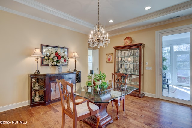 dining space featuring a chandelier, hardwood / wood-style flooring, a tray ceiling, and ornamental molding