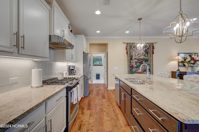 kitchen featuring white cabinetry, sink, stainless steel appliances, an inviting chandelier, and light hardwood / wood-style floors