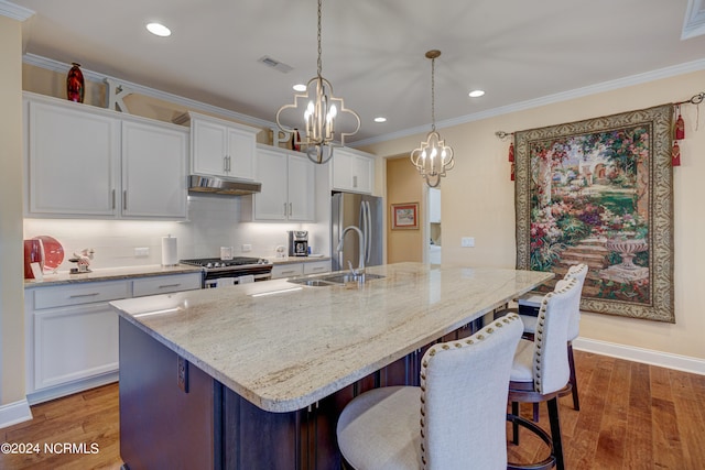 kitchen with hardwood / wood-style flooring, a center island with sink, sink, and appliances with stainless steel finishes