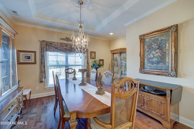 dining room with a tray ceiling, crown molding, hardwood / wood-style floors, and a chandelier