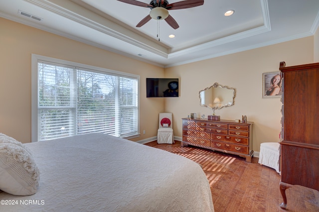 bedroom with hardwood / wood-style flooring, ceiling fan, crown molding, and a tray ceiling