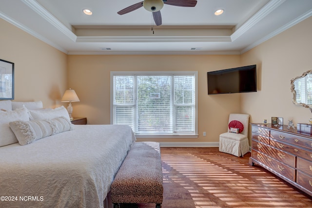 bedroom with ceiling fan, wood-type flooring, crown molding, and a tray ceiling