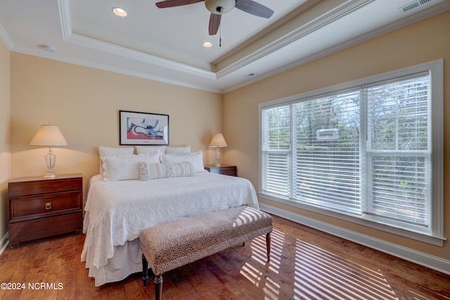 bedroom featuring hardwood / wood-style flooring, ceiling fan, ornamental molding, and a tray ceiling