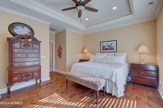 bedroom featuring hardwood / wood-style floors, a tray ceiling, ceiling fan, and ornamental molding