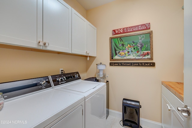 washroom with cabinets, light tile patterned flooring, and washing machine and clothes dryer