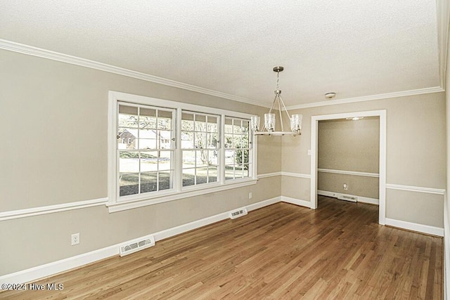 unfurnished dining area featuring wood-type flooring, crown molding, a notable chandelier, and a textured ceiling