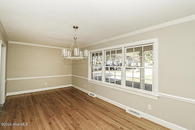 unfurnished dining area featuring hardwood / wood-style flooring, crown molding, an inviting chandelier, and a textured ceiling