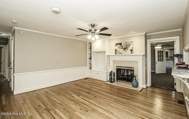 unfurnished living room featuring crown molding, wood-type flooring, a textured ceiling, ceiling fan, and a premium fireplace