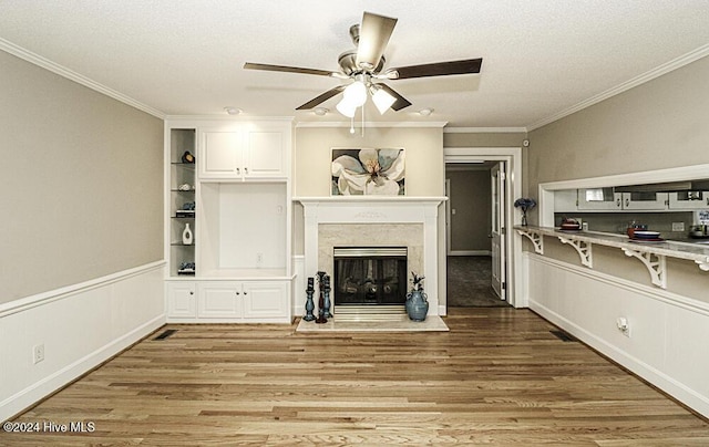 living room with ceiling fan, hardwood / wood-style floors, a high end fireplace, ornamental molding, and built in shelves