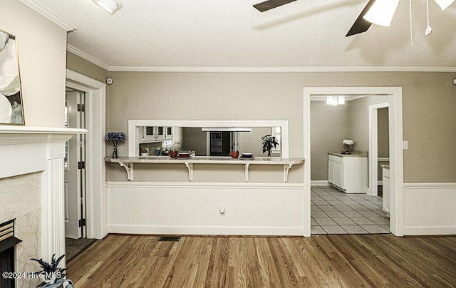 kitchen featuring crown molding, hardwood / wood-style flooring, a fireplace, and ceiling fan