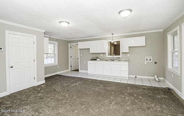 kitchen with pendant lighting, white cabinets, ornamental molding, light carpet, and a textured ceiling