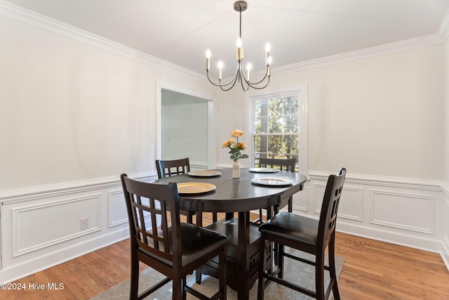 dining room featuring wood-type flooring, ornamental molding, and an inviting chandelier