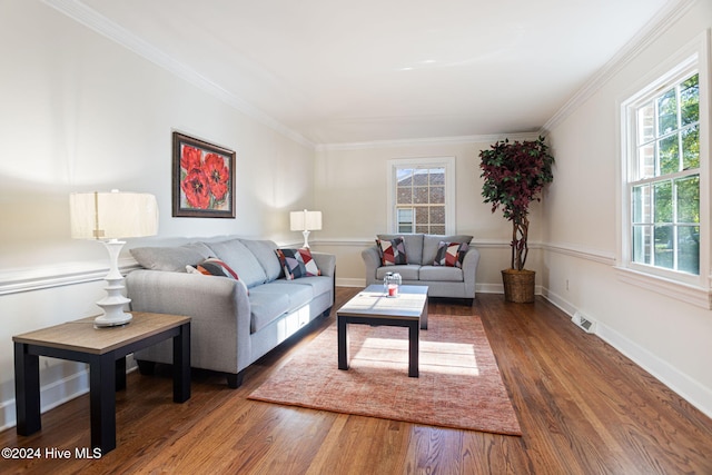 living room with a healthy amount of sunlight, ornamental molding, and dark wood-type flooring