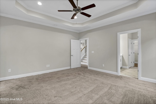 unfurnished bedroom with ornamental molding, connected bathroom, a raised ceiling, and light carpet