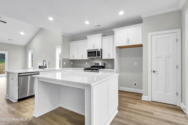 kitchen featuring sink, stainless steel appliances, white cabinets, a kitchen island, and kitchen peninsula