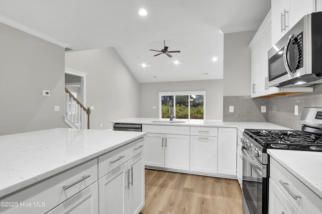 kitchen featuring white cabinets, decorative backsplash, light hardwood / wood-style floors, stainless steel appliances, and light stone countertops