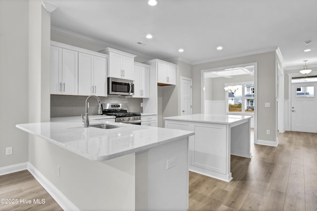 kitchen with crown molding, appliances with stainless steel finishes, white cabinetry, light stone countertops, and a kitchen island