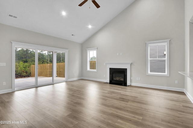 unfurnished living room featuring ceiling fan, high vaulted ceiling, and light wood-type flooring