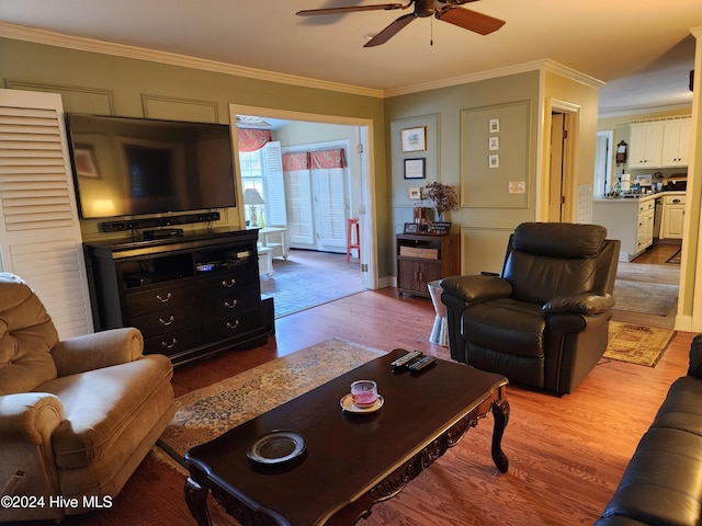 living room with crown molding, light hardwood / wood-style flooring, and ceiling fan