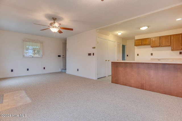 kitchen with kitchen peninsula, ceiling fan, and light colored carpet