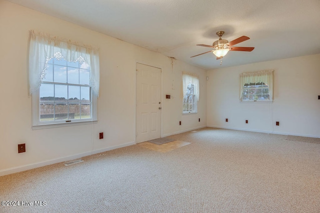 interior space featuring a wealth of natural light, ceiling fan, and light colored carpet