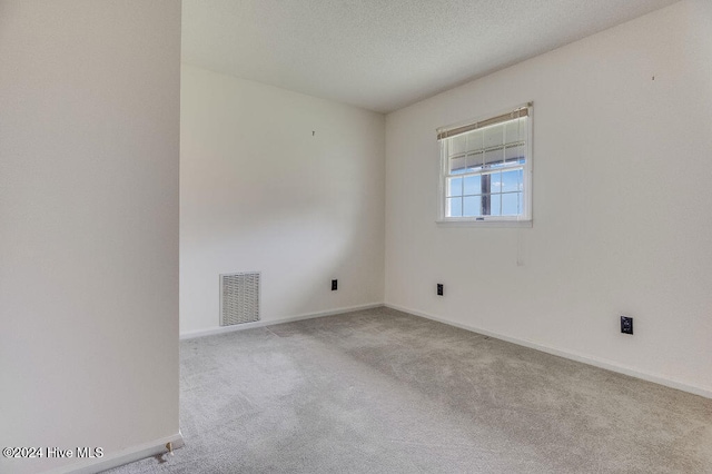 unfurnished room featuring light carpet and a textured ceiling