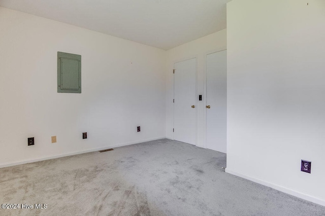 empty room featuring light carpet and electric panel