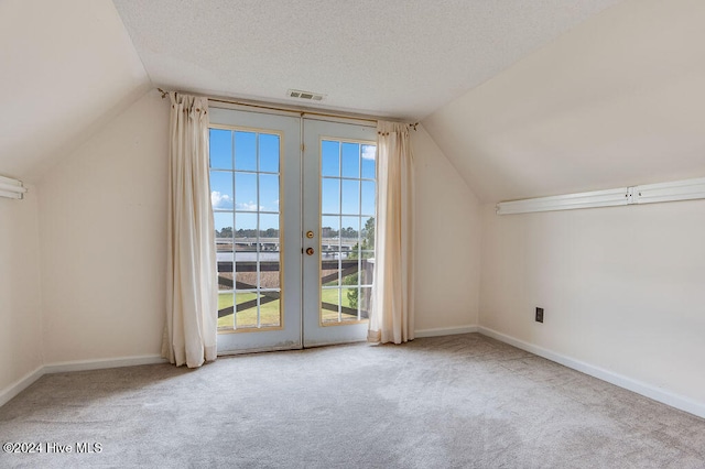 additional living space featuring plenty of natural light, a textured ceiling, light carpet, and french doors