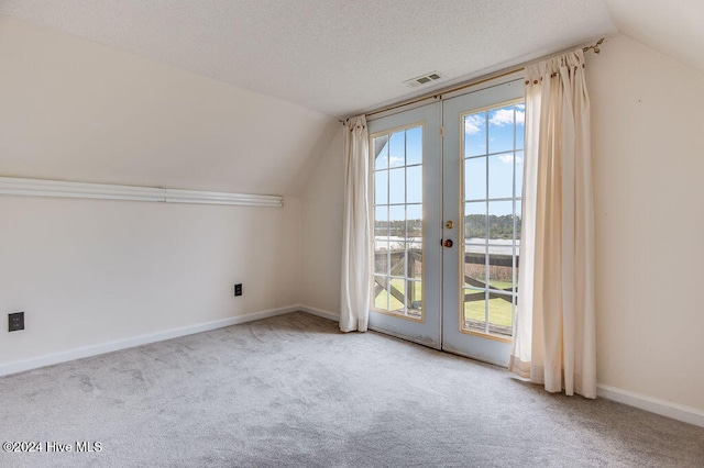 bonus room featuring light colored carpet, lofted ceiling, a textured ceiling, and french doors