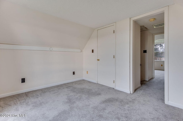 additional living space with light colored carpet and vaulted ceiling