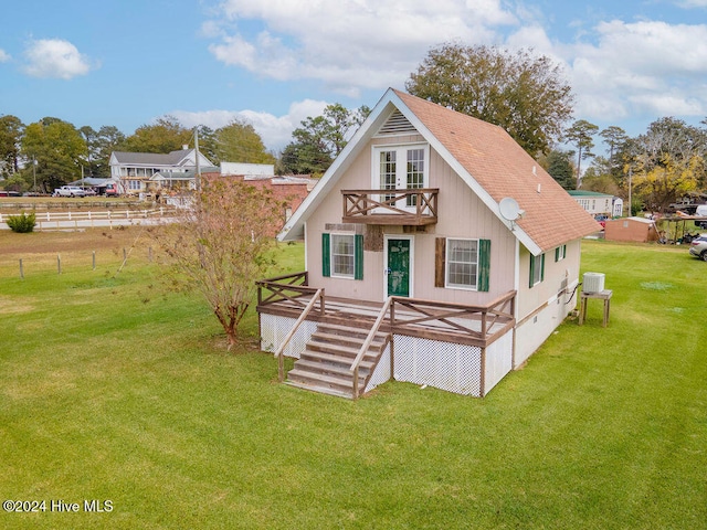 back of property with a yard, a balcony, and central AC unit