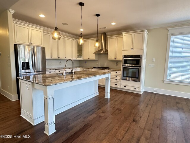 kitchen featuring wall chimney exhaust hood, a sink, glass insert cabinets, and pendant lighting