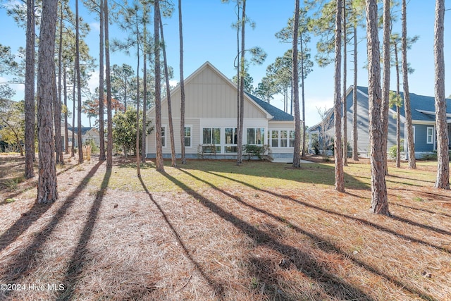 rear view of property with board and batten siding and a yard