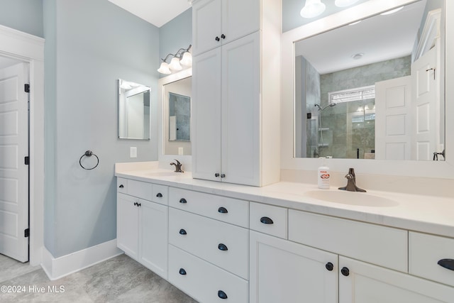 bathroom featuring double vanity, a stall shower, baseboards, and a sink