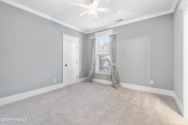 carpeted spare room with ceiling fan, baseboards, visible vents, and crown molding