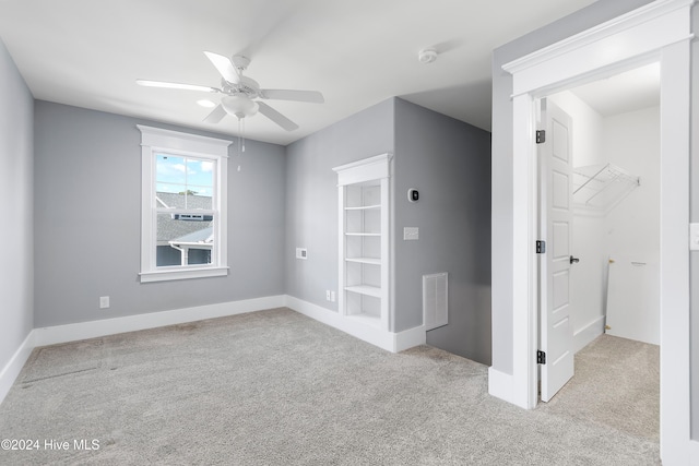 empty room with baseboards, a ceiling fan, visible vents, and light colored carpet