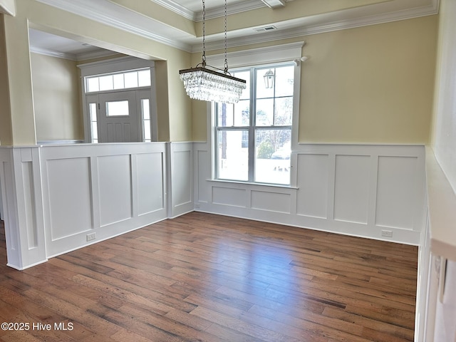 unfurnished dining area with dark wood-type flooring, visible vents, crown molding, and an inviting chandelier