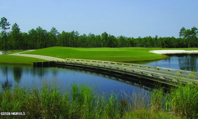 view of community with view of golf course, a water view, and a lawn