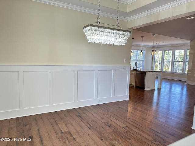 unfurnished dining area with a chandelier, dark wood-type flooring, crown molding, and a decorative wall