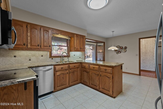 kitchen with sink, hanging light fixtures, stainless steel appliances, tasteful backsplash, and kitchen peninsula