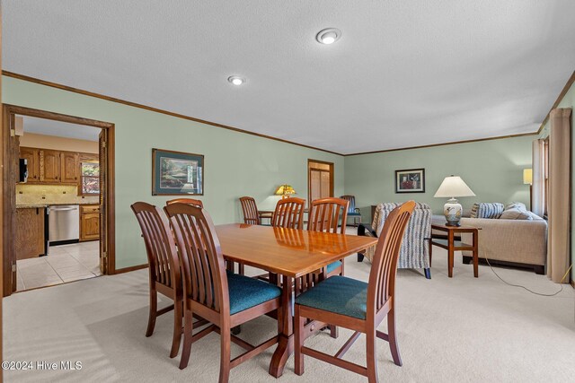 dining space with a textured ceiling, light colored carpet, and crown molding