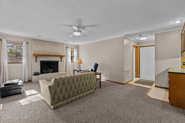 carpeted living room featuring ceiling fan, sink, a textured ceiling, a fireplace, and ornamental molding