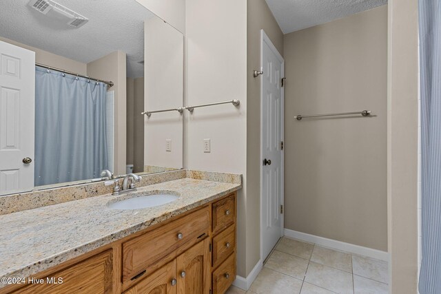 bathroom featuring tile patterned flooring, vanity, and a textured ceiling