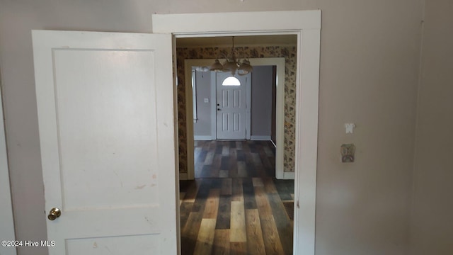 corridor featuring dark wood-type flooring and an inviting chandelier